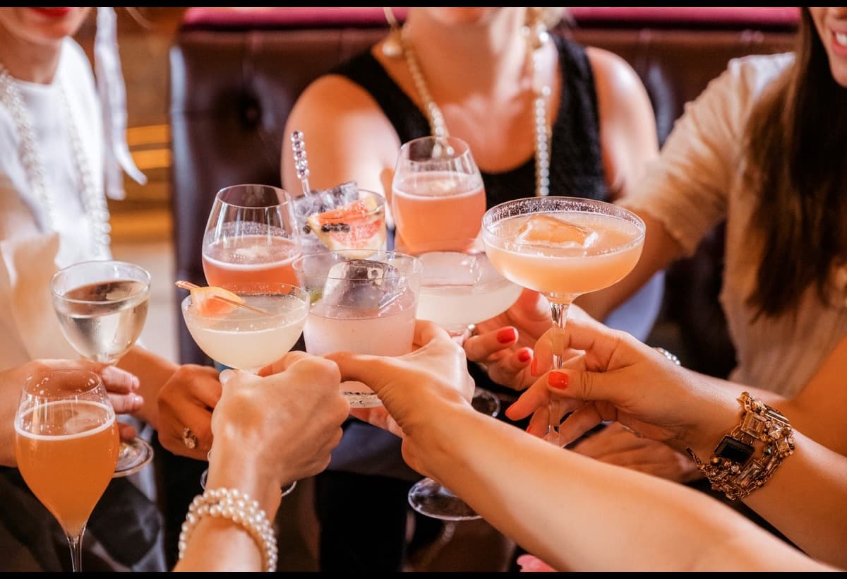 Several people reaching in to touch glasses over a table